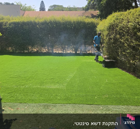 אדם גוזם גדר חיה בגינה ירוקה